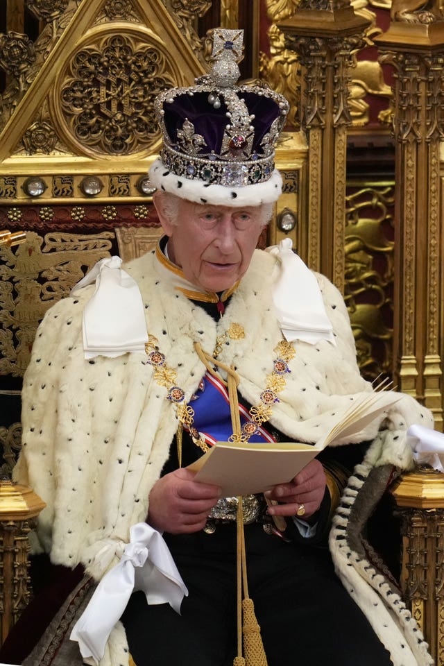 Charles, wearing a crown and robes, looks up as he reads the King’s Speech, during the State Opening of Parliament