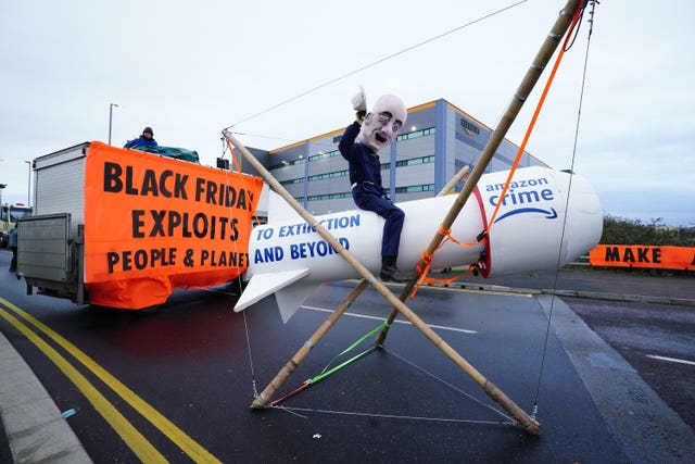 An activist from Extinction Rebellion, wearing a giant Jeff Bezos head, blocks the entrance to the Amazon centre in Tilbury, Essex