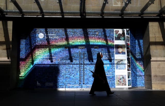 A woman walks past a Rainbows for the NHS mosaic made up of thousands of pictures and stories, submitted during the ongoing pandemic, which covers the windows and entrance to the Buchanan Galleries in central Glasgow, some six months on from the evening of March 23 when Prime Minister Boris Johnson announced nationwide restrictions