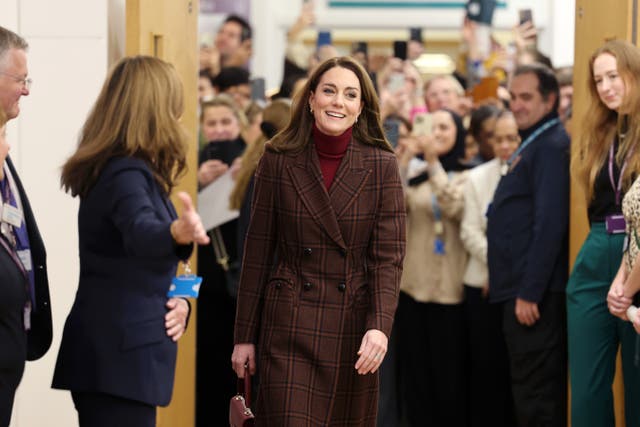 Smiling Kate walks through a hospital door watched by crowds of onlookers in the corridor