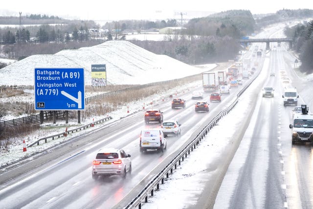 Motorists drive through sleet and snow along the M8