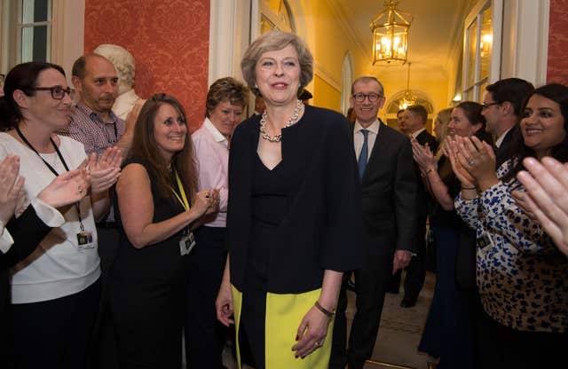 Staff in No 10 applaud Theresa May as she enters for the first time as prime minister followed by her husband, Philip. 