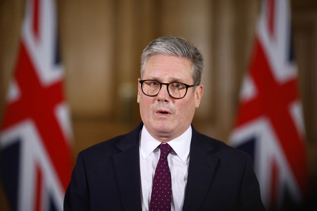 Prime Minister Sir Keir Starmer standing in front of Union Jacks