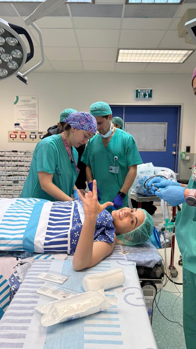 Emily Damari smiles at the camera as she prepares for surgery in an operating theatre