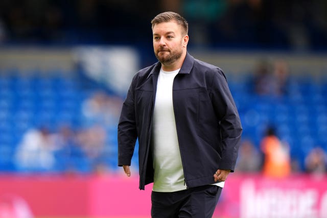 Alex Brooker walking across a football pitch