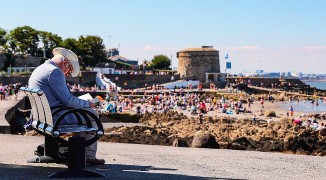 A man reads a book by himself during good weather at Seapoint beach in South Dublin on Sunday