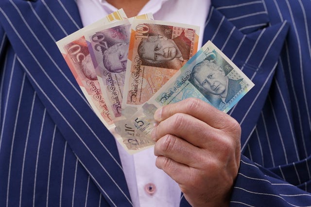 A person holds some of the newly released banknotes featuring the King’s portrait