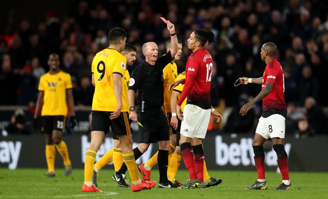 Match referee Mike Dean shows a red card and sends off Manchester United’s Ashley Young 