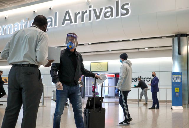 A masked passenger arrives at Heathrow in June