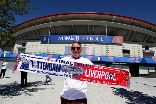 A Tottenham fan with a half-and-half scarf in front of the Wanda Metropolitano