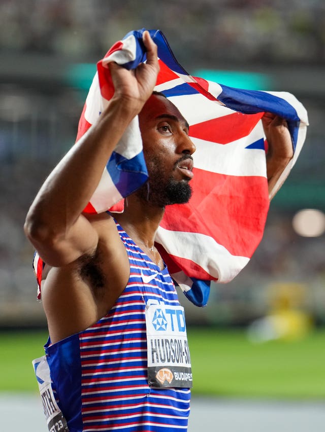 Matt Hudson-Smith drapes a Union Flag behind his head and looks in the distance 