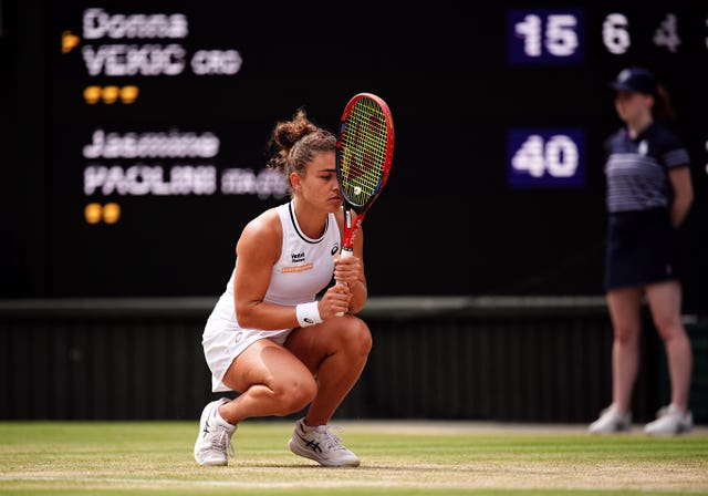 Jasmine Paolini crouches almost to her knees and holds her racket against her head in frustration