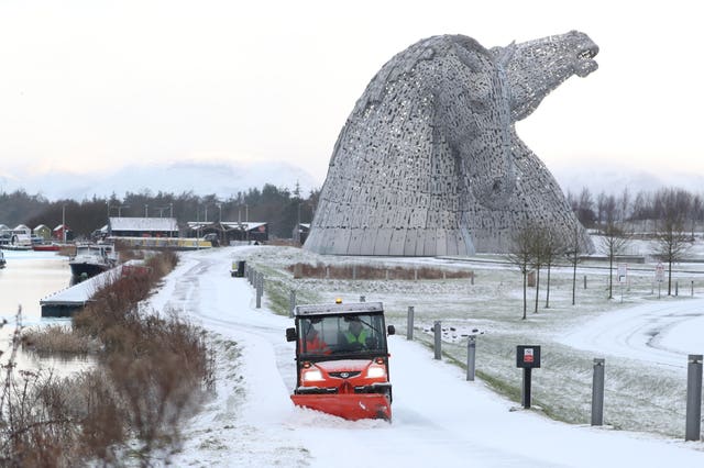 A staff member uses a vehicle to clear snow on a pathway at the Kelpies, near Falkirk in Scotland