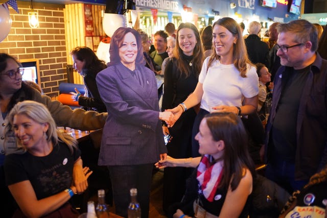 People pose for photos with a cardboard cutout of Kamala Harris