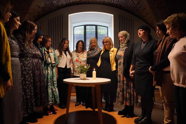 A group of women surrounding a lit candle