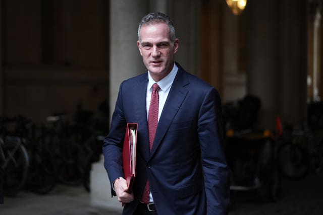 Peter Kyle exiting a building, with his red ministerial folder under his arm