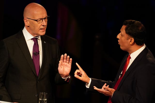 John Swinney and Anas Sarwar interacting, with both gesturing with their hands and speaking