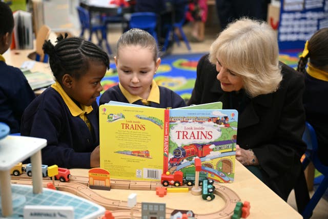 Camilla reading a book about trains with two children