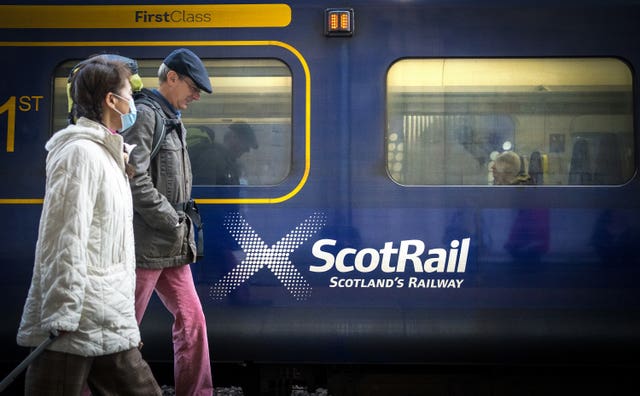 People walking on a platform past a ScotRail train