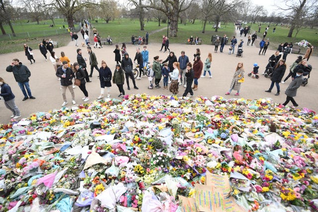 People viewing floral tributes left at the bandstand in Clapham Common, London, for Sarah Everard 