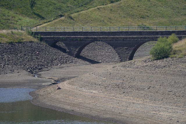 A person sits on the bank of near empty Dowry Reservoir close to Oldham 