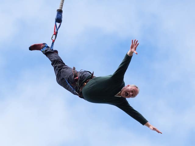 Ed Davey in mid-air with his arms out stretched during a bungee jump