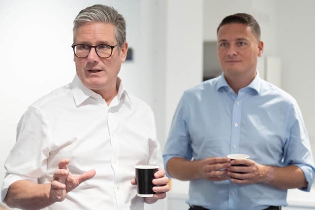 Wes Streeting in a blue shirt and Sir Keir Starmer in a white shirt chat to people off frame