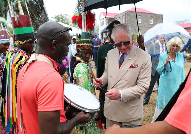 The King, tries out a drum at a reception at Government House on Nevis during a visit when he was the Prince of Wales in 2019