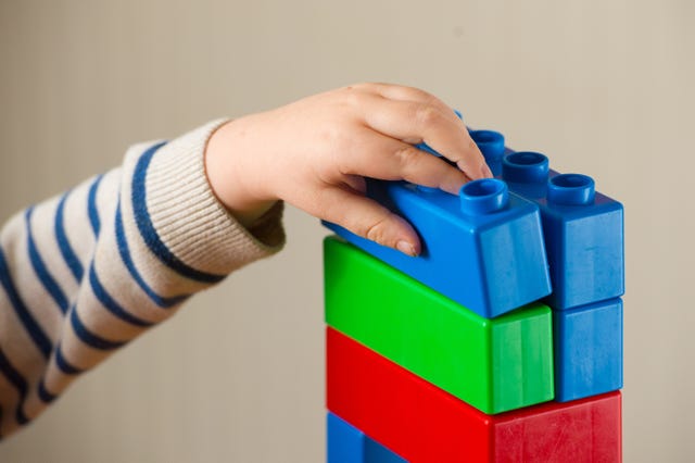 Child's hand playing with coloured plastic bricks