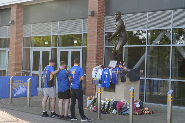 Fans look at flowers and shirts left in front of a photograph of former Leeds Rhinos player Rob Burrow outside Headingley Stadium in Leeds