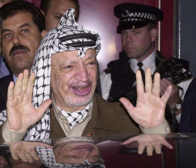 Yasser Arafat smiles as he gets into a car