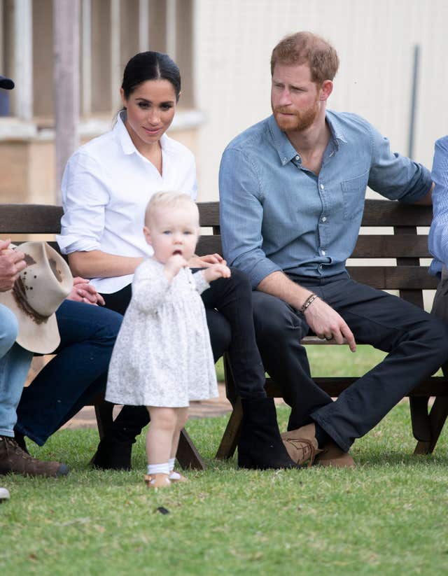 Harry and Meghan look at Ruby Caroll as they visit a local farming family, the Woodleys in Dubbo,during their tour Australia last year
