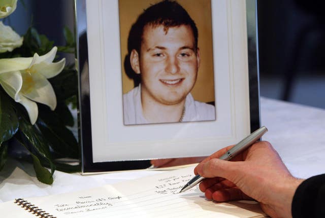 A man signs a book of condolence for Pc Ronan Kerr