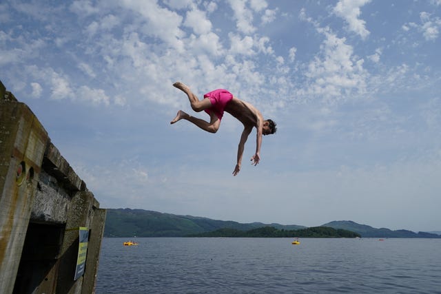 People jump from a pier into the water of Loch Lomond