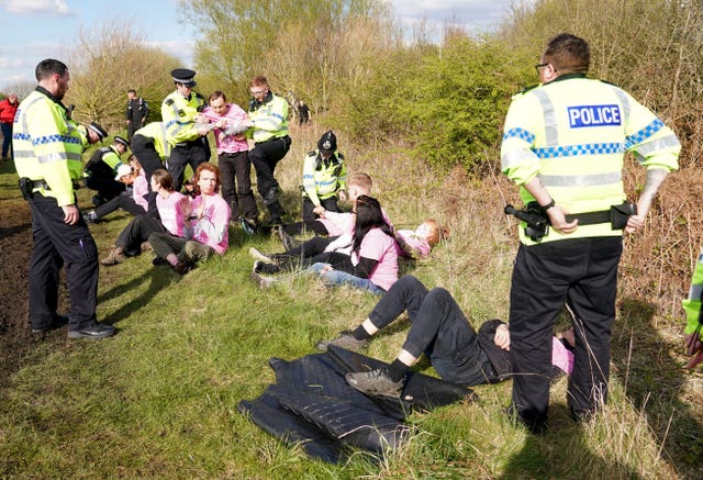 Protesters are detained by police on the course perimeter 