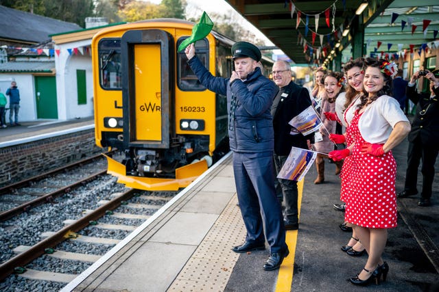 Transport Secretary Grant Shapps wears a hat, waves a flag and whistles off a GWR Dartmoor Line train from Oakhampton station