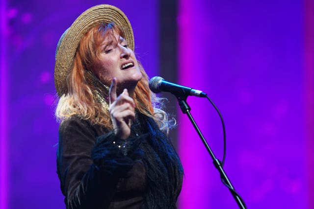 Eddi Reader singing at a microphone, with head thrown back, wearing a straw boater hat