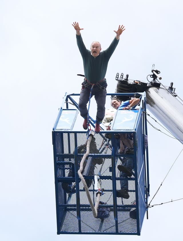 Sir Ed Davey diving from a platform for a bungee jump