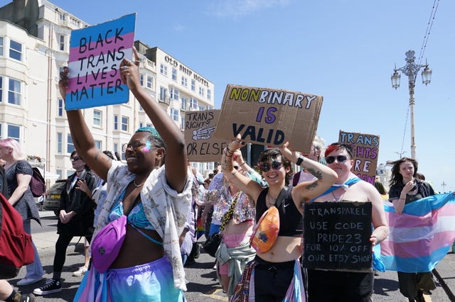 People hold signs as they take part in a Trans Pride protest march in Brighton