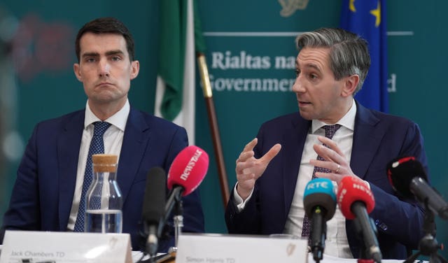 Jack Chambers and Simon Harris seated at a table, with several microphones positioned in front of them