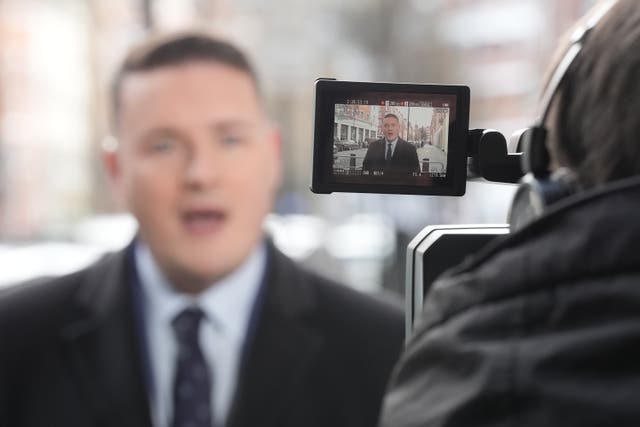 Wes Streeting captured in a video camera's viewfinder in the foreground while he is speaking to the media in the background