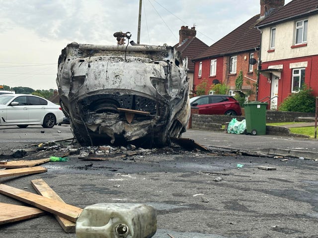 A torched car lies in the road