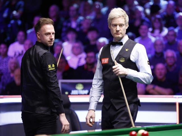 Judd Trump, left, and Neil Robertson look at the table as Robertson prepares for a shot