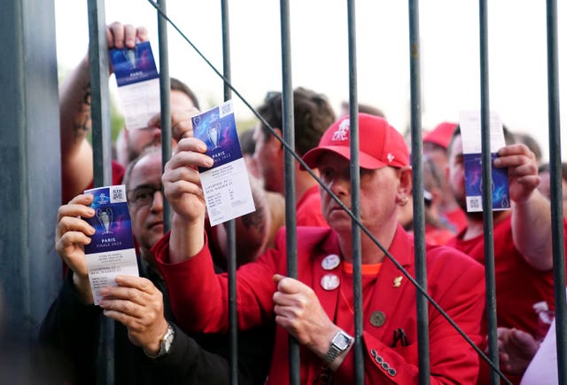 Liverpool fans show their tckets through a fence