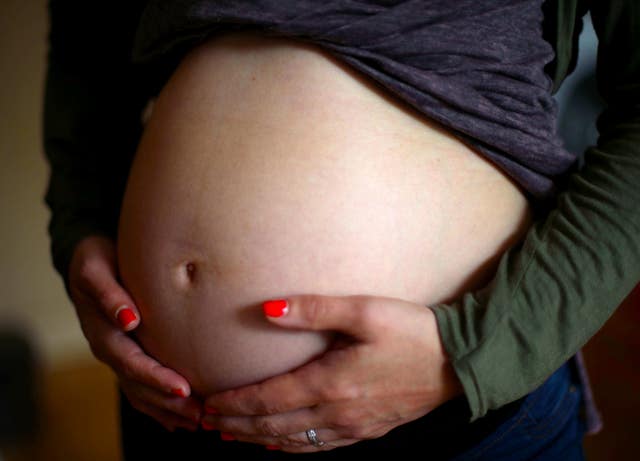 A pregnant woman holds her stomach (Yui Mok/PA)