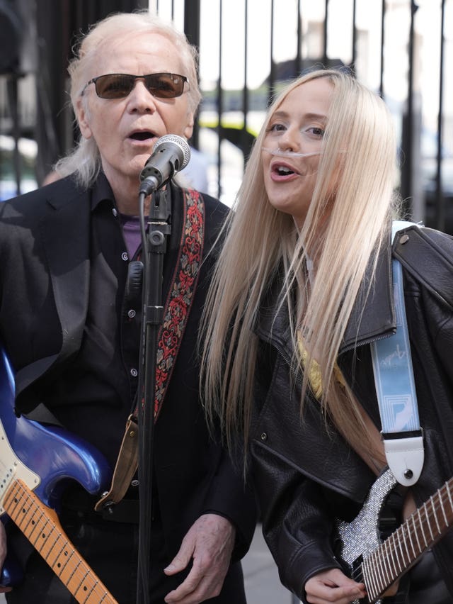Brian Hyland and Ashleigh Harley playing guitars and singing outside Downing Street.