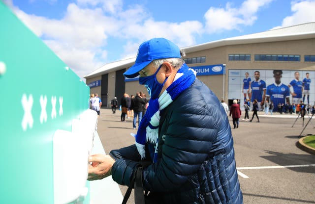 A Brighton fan uses hand sanitiser at a pilot event for the return of spectators