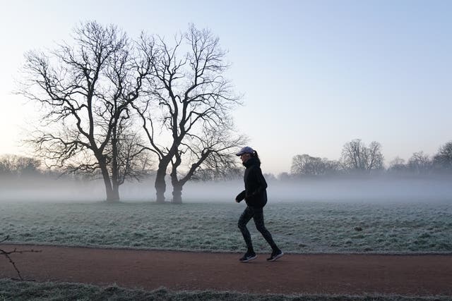 A jogger runs in the morning fog of Morden Hall Park, south London