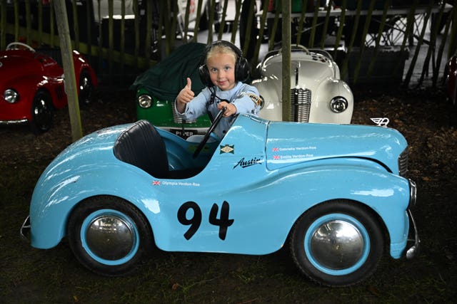 Emilia Verdon-Roe, aged six, with her thumb up standing beside a small blue car as she prepares to race in the Settrington Cup 