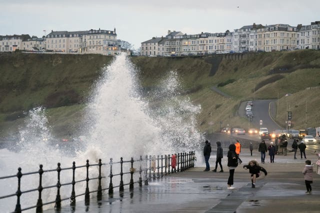 People walk along a sea wall during bad weather 